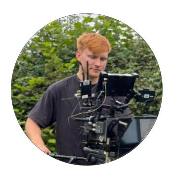 Aman standing behind a film camera